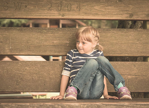 Foto Mädchen sitzt an Zaun