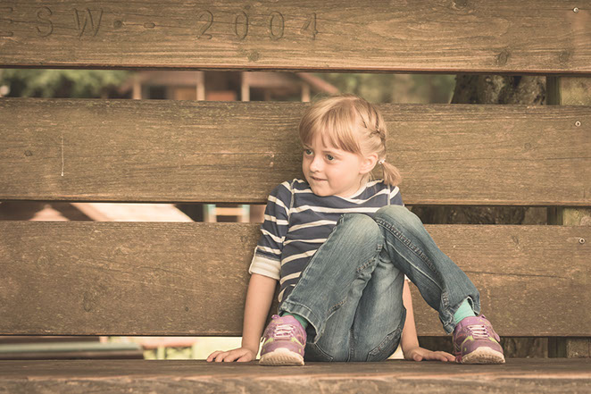 Foto Mädchen sitzt an Zaun